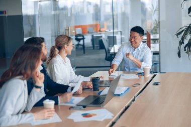 Genç ve başarılı bir iş adamı takımı modern bir ofiste birlikte çalışıyor ve iletişim kuruyor.