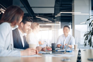 Güzel iş adamları ofis konferansı boyunca aletler kullanıyor, konuşuyor ve gülümsüyor.