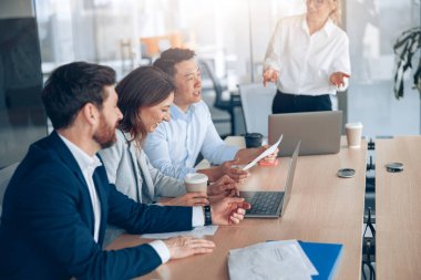 Ofisteki iş arkadaşlarıyla iş görüşmesinde gülümseyen kendine güvenen iş kadınına yakın dur. 