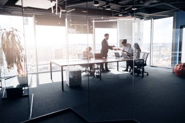 Masanın yanında duran insanlar, ofiste birlikte çalışan ve iletişim kuran genç iş adamları.