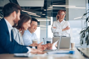 Ofisteki meslektaşlarıyla iş toplantısına bakan kendine güveni tam bir bayan patron. 