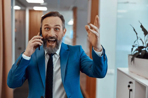 Handsome Caucasian businessman talking on mobile phone in modern office — ストック写真