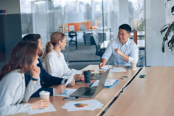 Genç ve başarılı bir iş adamı takımı modern bir ofiste birlikte çalışıyor ve iletişim kuruyor.
