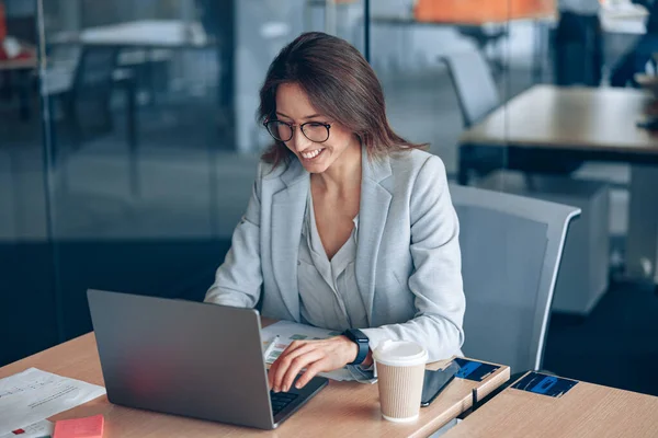 Sonriente dama de negocios que trabaja en el ordenador portátil en la empresa corporativa en la oficina moderna —  Fotos de Stock