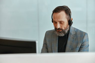 Kulaklık takan ve ofiste çalışan adam.