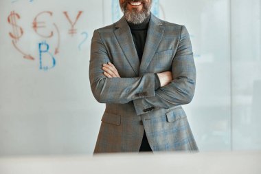 Ofiste gülümseyen yetişkin bir adam kameraya bakıyor.