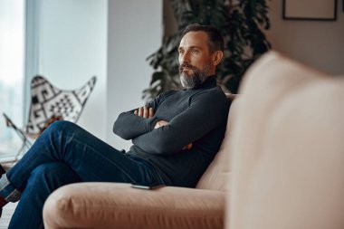 Yetişkin bir adam evinde dinleniyor.