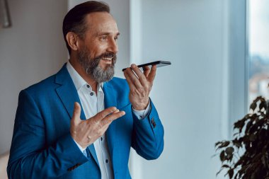 Mavi takım elbiseli başarılı bir iş adamı cep telefonuyla konuşuyor, kopyalama alanı