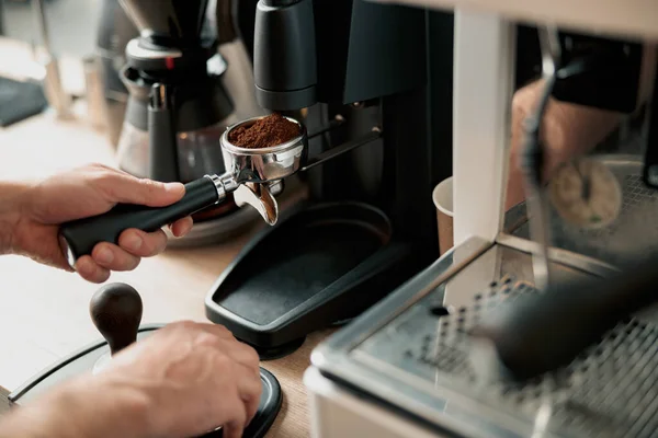 Close-up of male hand holding portfilter near coffee grinder — Stock Photo, Image