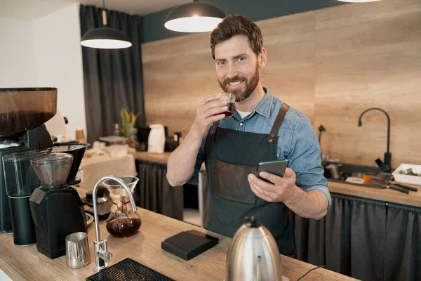 Kahve içen yakışıklı barista öğle yemeği boyunca sosyal medyada geziniyor.