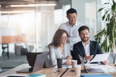 Gülümseyen işadamları kahve içer ve grafikler ve grafiklerle belgeleri tartışırlar. 