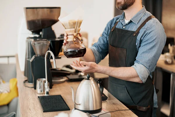 barista offering filter coffee to customer while standing at counter