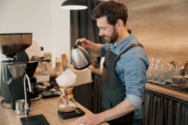 Barista, elle damlatan bira makinesiyle kahve yapmak için su dolduruyor.
