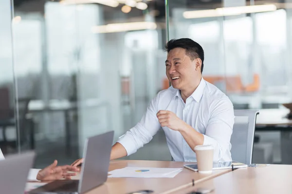 Positive Asian businessman listening his colleagues on meeting in modern office — ストック写真