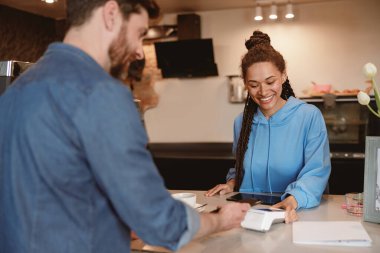 Kafede kahvesini ödeyen bir erkek müşteri. Barda içki satan kadın barmen. Arka..