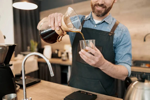 Smiling barista pouring filtered coffee into a glass — Stock Photo, Image