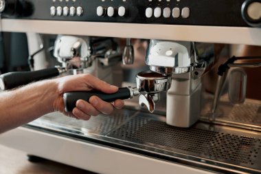 Kahve öğütücüsünün yanında erkek portföy taşırken yakın plan.