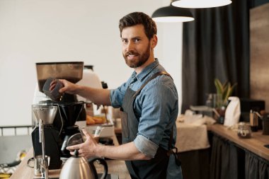 Barista kahve makinesinin tankına öğütülmesi için kahve çekirdeği koyuyor.