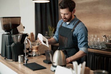 Kahveci kahve makinesinin kahve makinesinin tankına kahve çekirdeği doldurur.