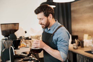 Güzel sakallı yakışıklı barista kafeteryada filtre kahve kokuyor.
