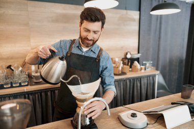 Barista, elle damlatan bira makinesiyle kahve yapmak için su dolduruyor.