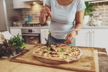 Cropped shot of woman making traditional homemade pizza at home