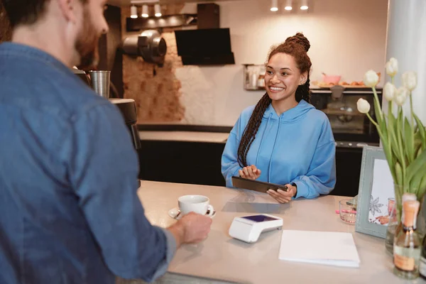 Kafeteryadaki müşterinin arka planda bir fincan kahveyi götürüşü. Servis yapan bayan barista..