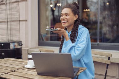 Genç ve çekici bir bayan kafede cep telefonundan sesli mesaj yolluyor. Ses sohbeti.
