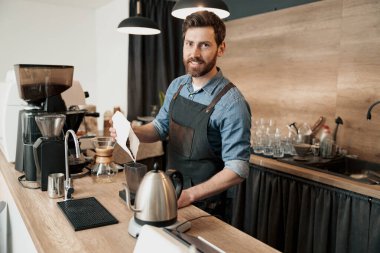 Barista kahve makinesinin tankına öğütülmesi için kahve çekirdeği koyuyor.
