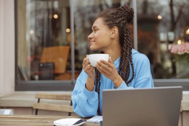 Hayalperest, genç, melez, stil sahibi bir kadın. Saçları örgülü, elinde bir fincan kahveyle hayal kuruyor..