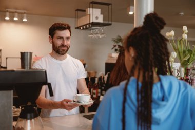 Barda bayan müşteriye kahve servisi yapan neşeli yakışıklı garson. Kahve konsepti satmak.