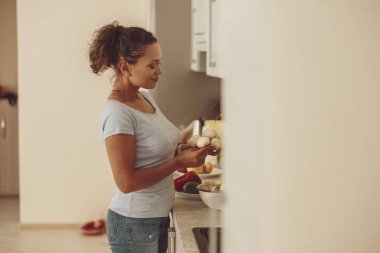 Bir kadın mutfakta lavabonun önünde duruyor ve elinde mantar tutuyor.