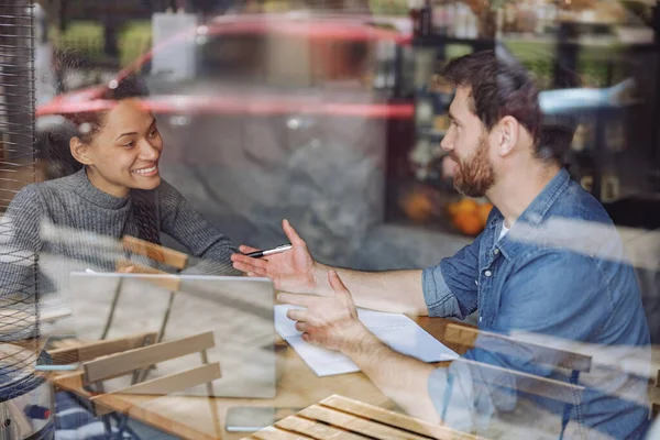 Happy sonrió a un par de startupers hablando y compartiendo ideas en la mesa del café. Reunión de negocios. — Foto de Stock