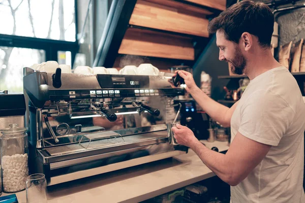 Kafkasyalı, kafeteryadaki profesyonel makinede kahve yapan erkek kahveci gülümsedi. Kafe işi.