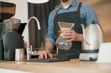 Kahveci elinde filtre kahve yapmak için cam bir kap tutuyor.