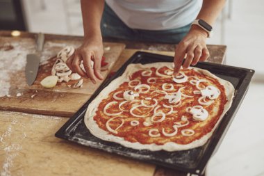 Pizza üzerine mantar ve soğan serpiştiriyorum. Fırında yemek pişirmek için yatıyorum.