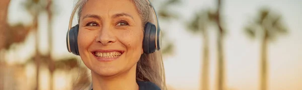 stock image Sporty female in headphones and black hoodie on the beach