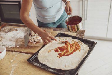 Mutfakta mantar ve domates sosu kullanarak ev yapımı pizza.