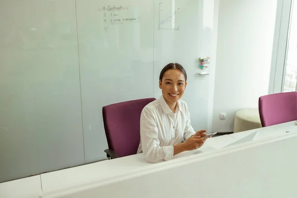 Uśmiechnięta Azjatycka Bizneswoman Siedząca Sali Konferencyjnej Trzymająca Telefon Wysokiej Jakości — Zdjęcie stockowe