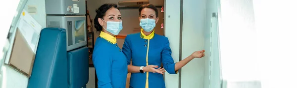 Vrouwelijke Stewardessen Met Beschermende Gezichtsmaskers Terwijl Bij Vliegtuigdeur Staan Passagiers — Stockfoto