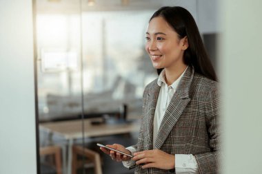 Ofisinde telefonu olan gülümseyen Asyalı kadın işçinin portresi. Bulanık arkaplan