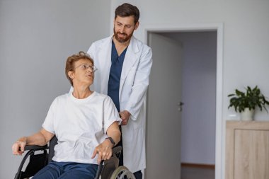 Profesyonel doktor tekerlekli sandalyedeki hastayı klinikteki hastane koğuşuna getirdi. Yüksek kalite fotoğraf