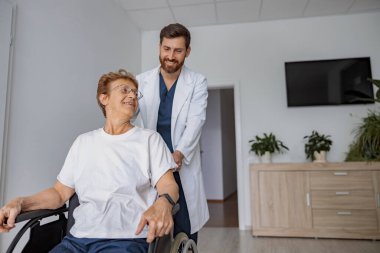 Profesyonel doktor tekerlekli sandalyedeki hastayı klinikteki hastane koğuşuna getirdi. Yüksek kalite fotoğraf