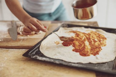 Ev yapımı pizza masanın üzerine serpilmiş domates sosu ile