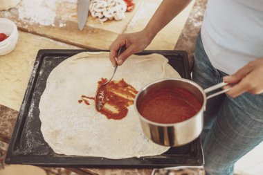 Evde mutfakta mantarlı ve domates soslu pizza pişirmek.