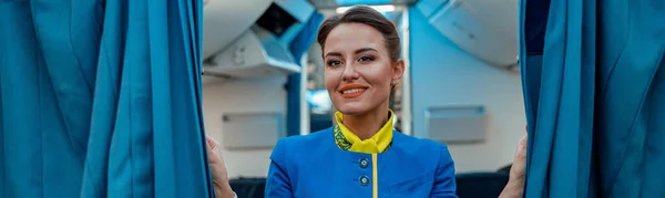 Radosny Stewardessa Mundurze Stewardessy Patrzy Kamerę Uśmiecha Się Trzymając Zasłony — Zdjęcie stockowe