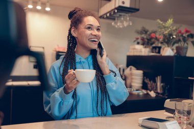 Tezgahtaki güzel bayan barmen dinleniyor ve cep telefonuyla konuşuyor. Kahve molası.