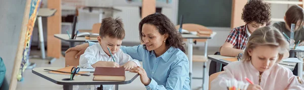 Szczęśliwy Nauczyciel Pomaga Dzieciom Podstawówce — Zdjęcie stockowe