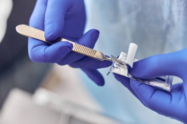 Confident doctor is preparing a scalpel for dental operation