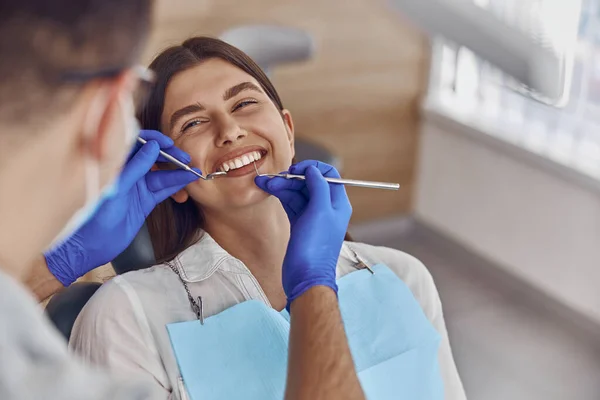 Profesyonel doktor modern diş kliniğinde kadınların dişlerini kontrol ediyor.